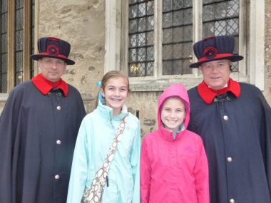 Two Beefeaters at the Tower of London pose with two girls