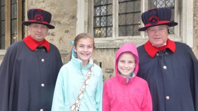 Two Beefeaters at the Tower of London pose with two girls