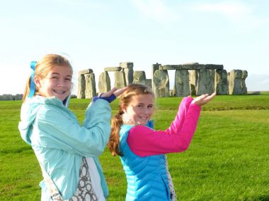 Two girls posed like they are holding Stonehenge in the palms of their hands