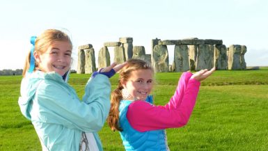 Two girls posed like they are holding Stonehenge in the palms of their hands