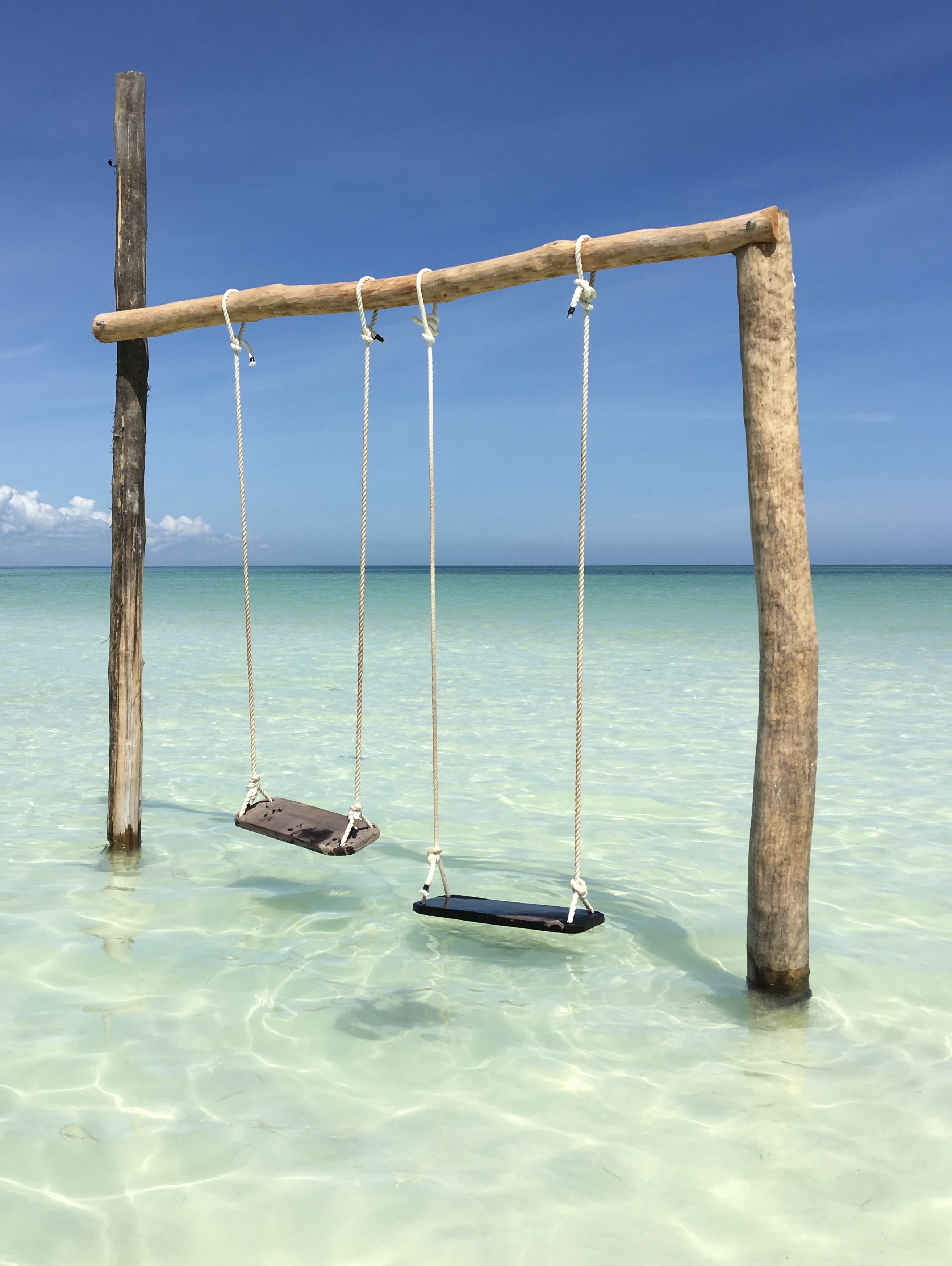 Holbox Island hanging swings over crystal clear shallow beach water