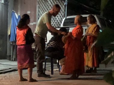 Man giving alms to monks during Tak Bat