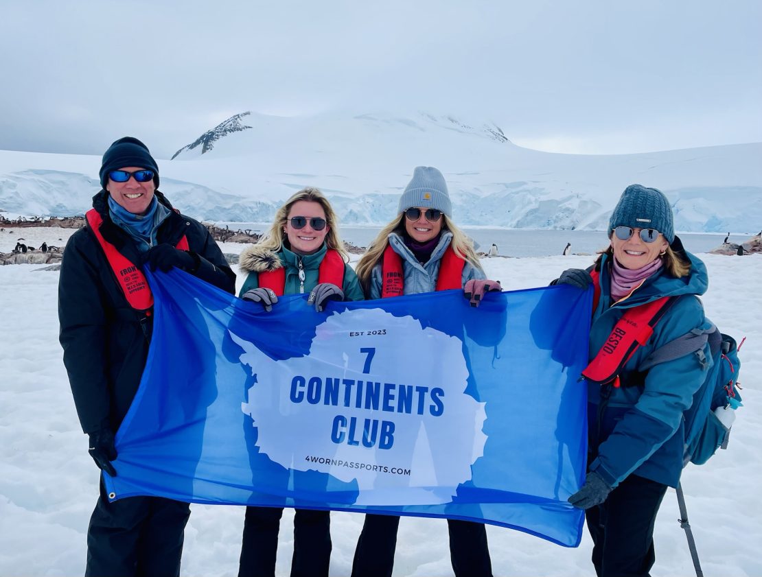 The McIntyres hold a 7-Continents Club flag in Antarctica
