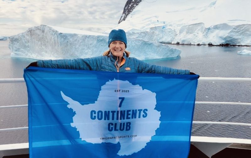 Kellie holding the 7 Continents Club flag in Antarctica