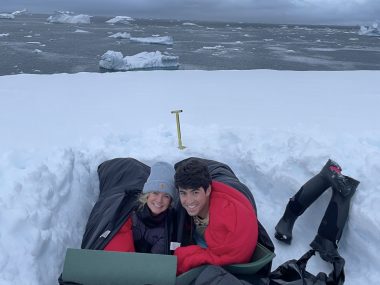 Couple in sleeping bags in snow camping in Antarctica
